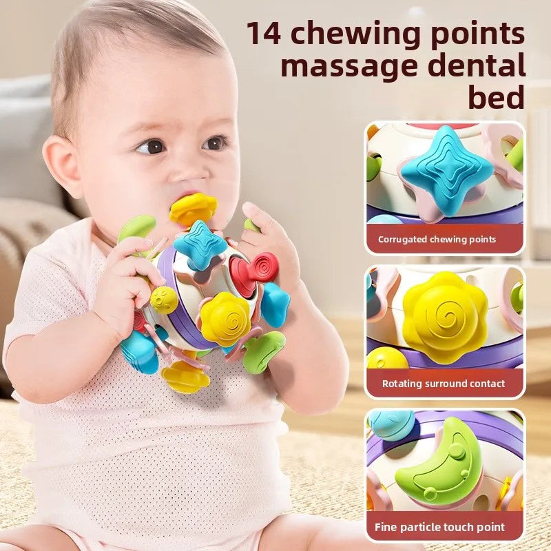A baby chewing on the yellow part of a colorful silicone rattle cube, which has 14 different chewing points for teething relief.