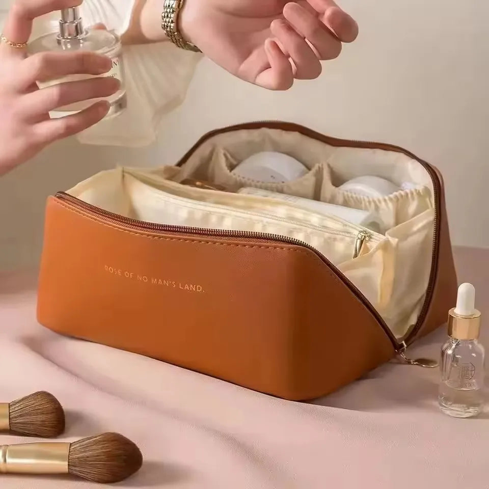 A person using the brown PU leather LuxeCase makeup bag, showing its spacious interior with multiple compartments.
