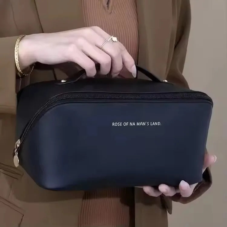 A person holding the stylish black PU leather LuxeCase makeup bag, showcasing its handle and minimalist design.