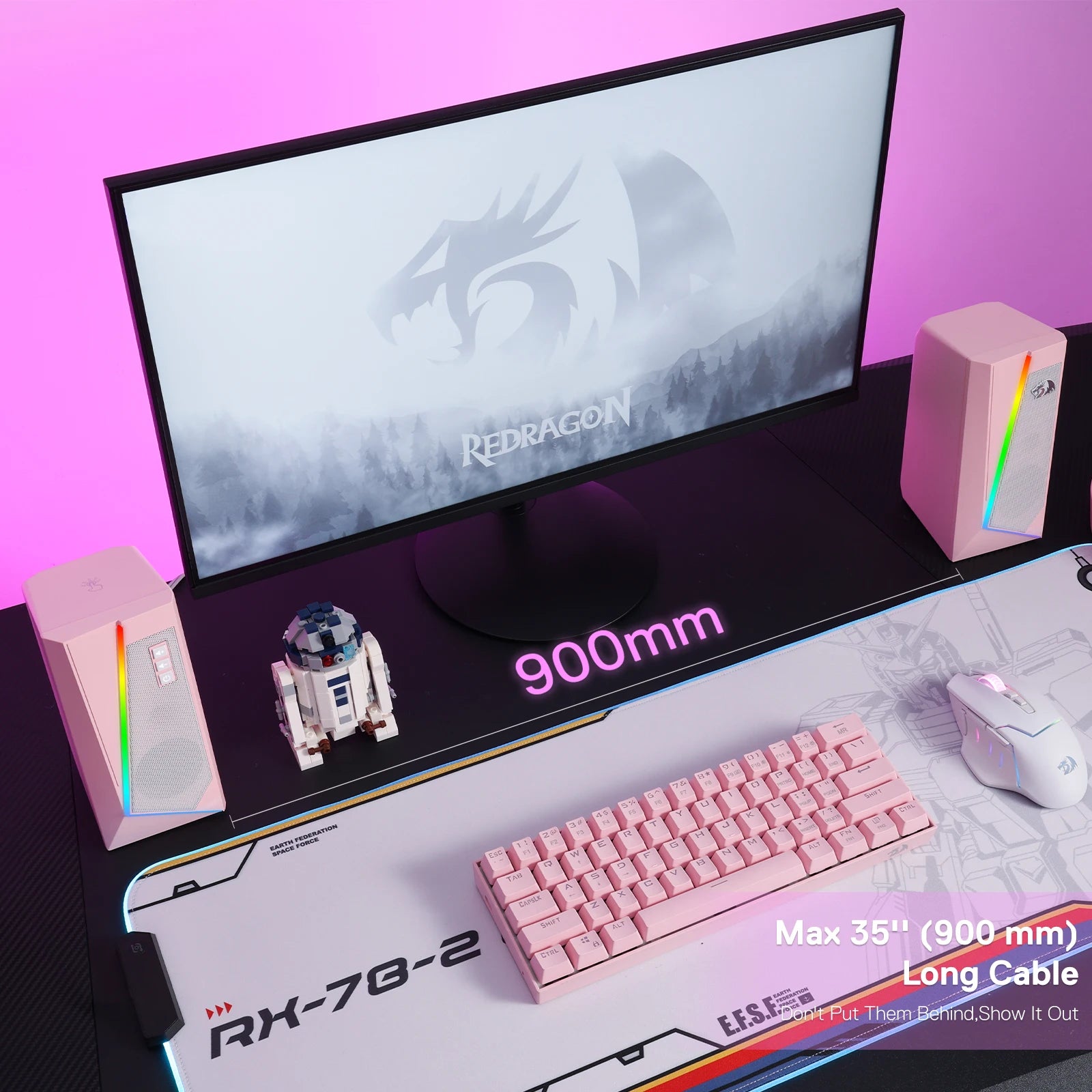 A pink-themed gaming desk setup featuring the pink Redragon GS520 speakers, a pink keyboard, and a large mousepad.