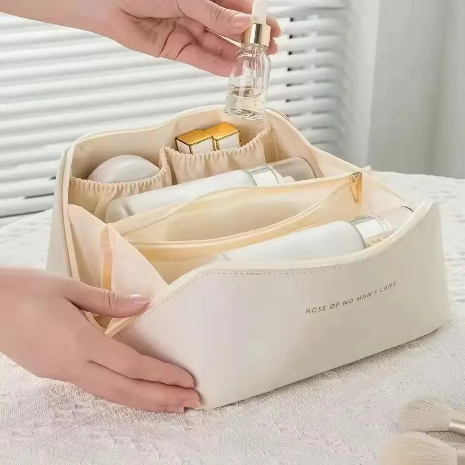 A hand placing a serum bottle into one of the organised compartments of the cream-white LuxeCase makeup bag.