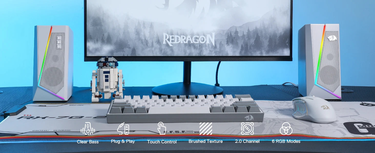 A full gaming desk setup featuring the white Redragon GS520 speakers, a keyboard, mouse, and monitor.