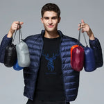 A model holding up five small, portable pouches containing the packed-down ArcticWave lightweight down jacket in various colors.