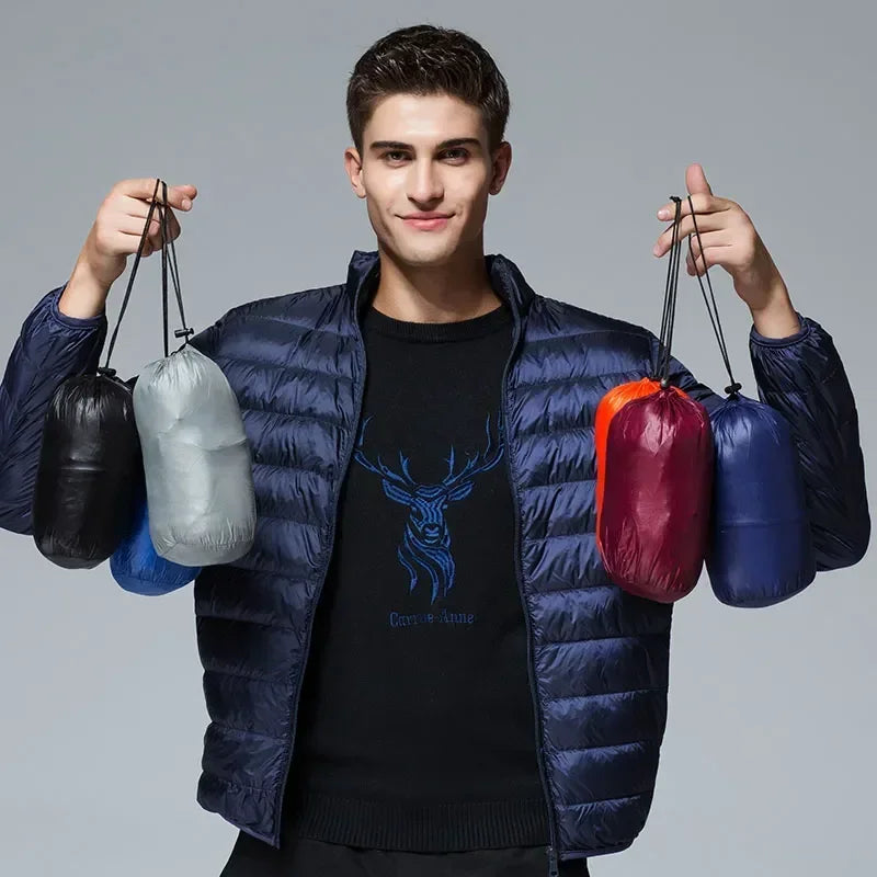 A model holding up five small, portable pouches containing the packed-down ArcticWave lightweight down jacket in various colors.