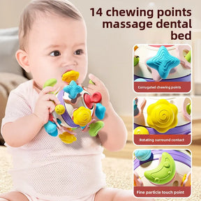 A baby chewing on the yellow part of a colorful silicone rattle cube, which has 14 different chewing points for teething relief.