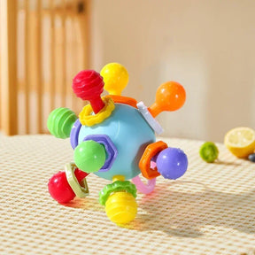 The blue and red version of the silicone sensory rattle toy on a checkered surface.