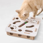 A ginger cat peering into the holes of a beige felt interactive puzzle box, trying to get the toys inside.