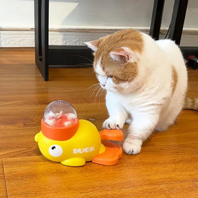 A white and orange cat actively playing with the yellow duck toy by pressing the pedal with its paw