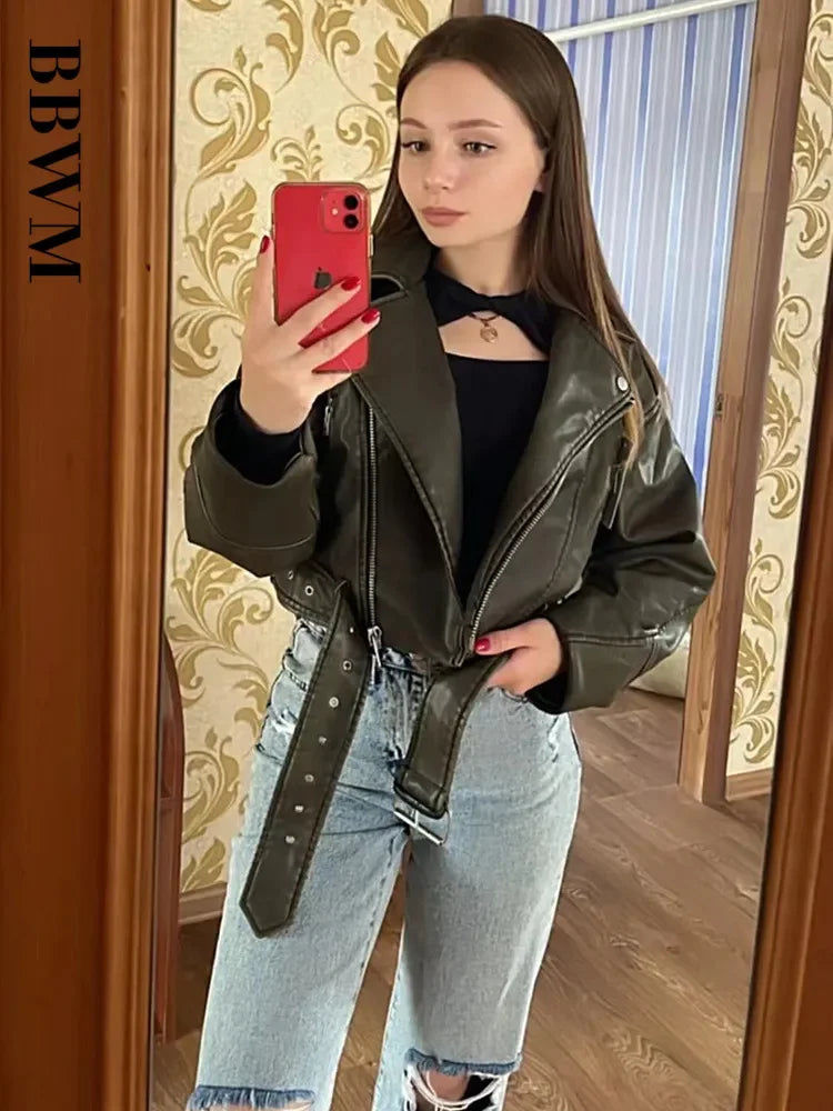 A mirror selfie of a customer wearing the olive green faux leather moto jacket with ripped jeans.