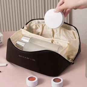 The dark brown LuxeCase makeup bag open to show its spacious interior and internal zippered pocket.