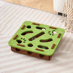 The square-shaped interactive cat puzzle box in a green and brown felt material, placed on a striped rug.