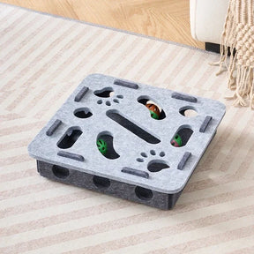 The square-shaped interactive cat puzzle box in a light and dark grey felt material.