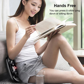 A woman reading a book while using the electric massager hands-free against her lower back for waist support.