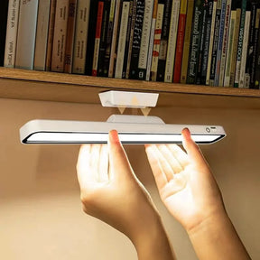 A person attaching the magnetic LED light bar under a bookshelf for easy, bright illumination.