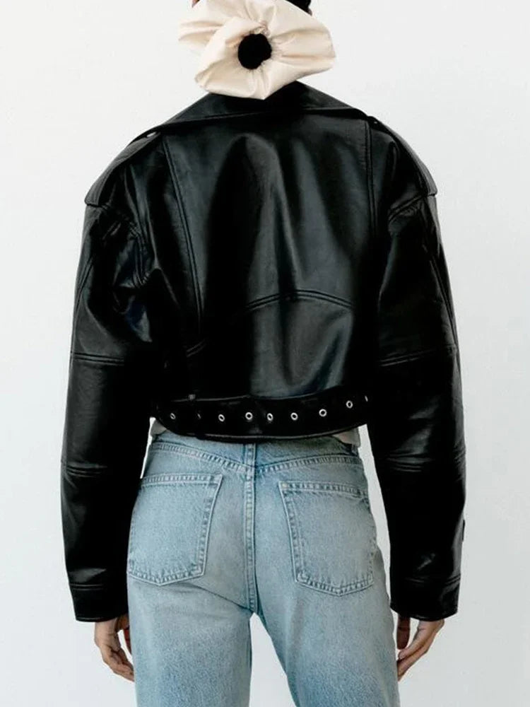 A model wearing the oversized black faux leather jacket with blue jeans, shown from the back.