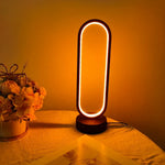 A modern oval-shaped LED lamp with a warm light, placed on a table as a decorative piece.