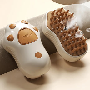 The Pawstrip paw-shaped pet steamy brush in brown and white, showing the steam function on its soft comb teeth.