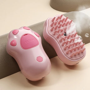 The Pawstrip paw-shaped pet steamy brush in pink, with steam rising from the soft comb teeth.