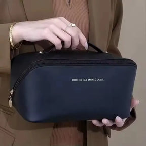 A person holding the stylish black PU leather LuxeCase makeup bag, showcasing its handle and minimalist design.