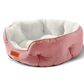 A clean product shot of the round pink version of the pet bed, showing its soft white fleece interior.