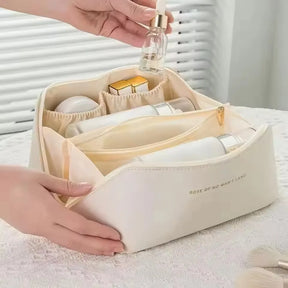 A hand placing a serum bottle into one of the organised compartments of the cream-white LuxeCase makeup bag.