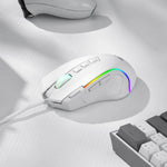 The white Redragon M612 gaming mouse on a textured white desk next to a keyboard, showing its RGB lighting.